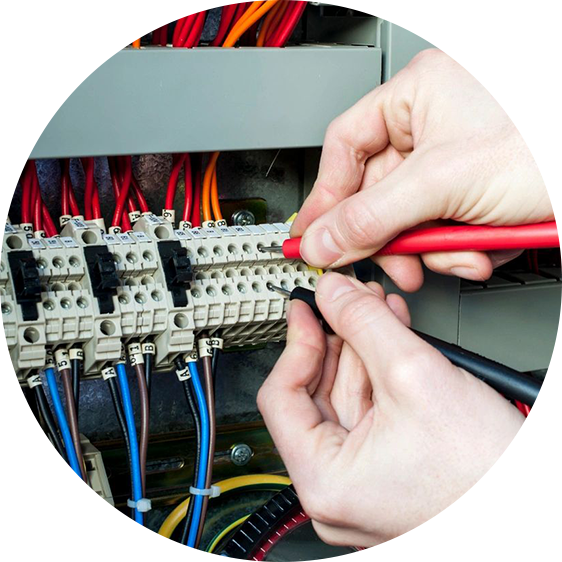 A person is working on electrical wiring in an industrial setting.