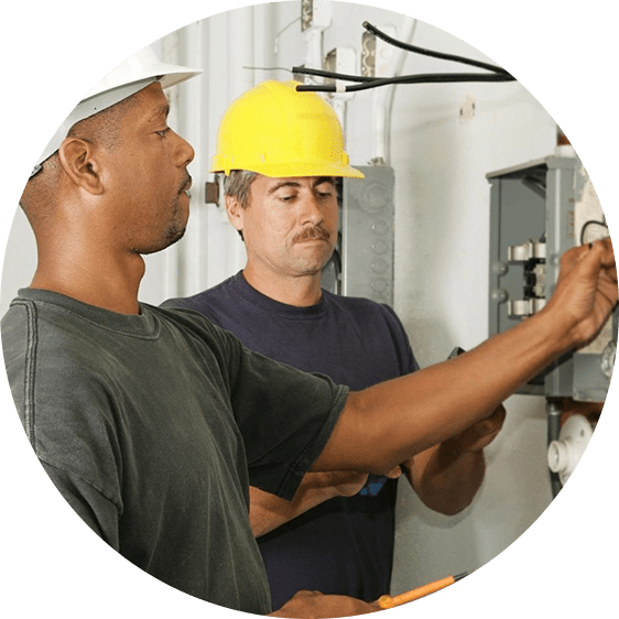 Two men in hard hats working on a circuit board.