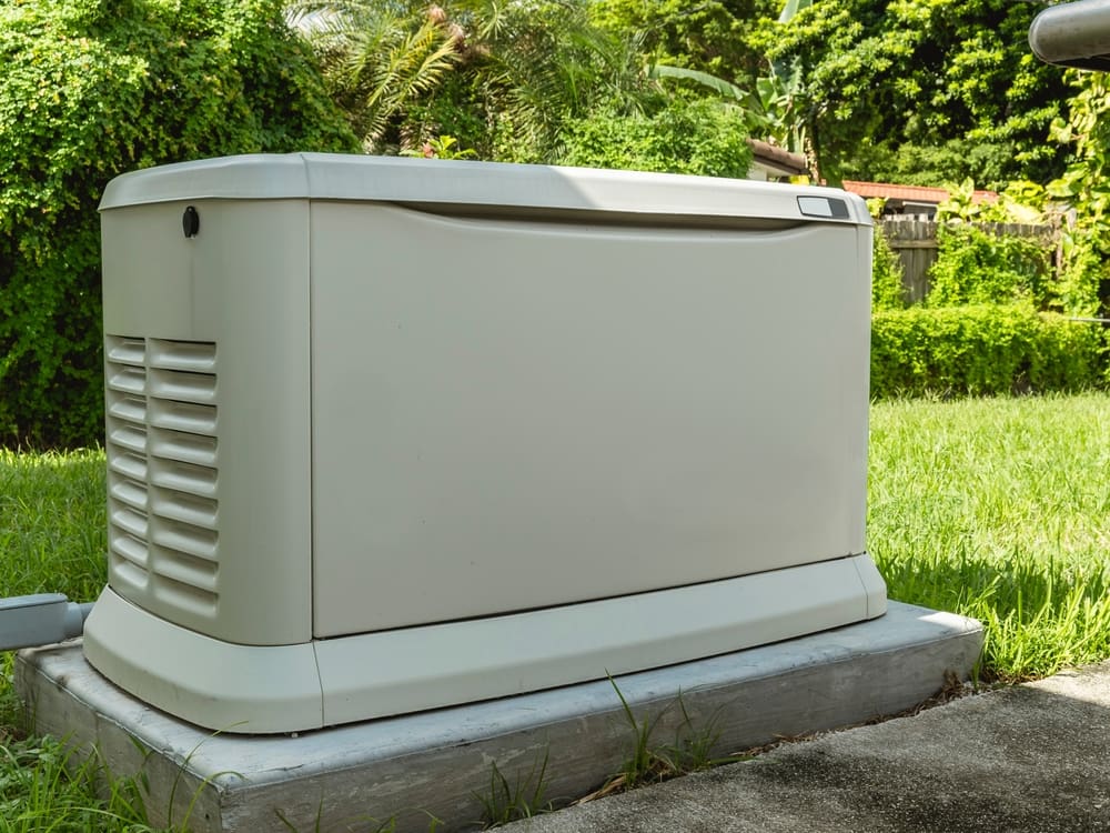 A generator sitting on top of concrete near grass.