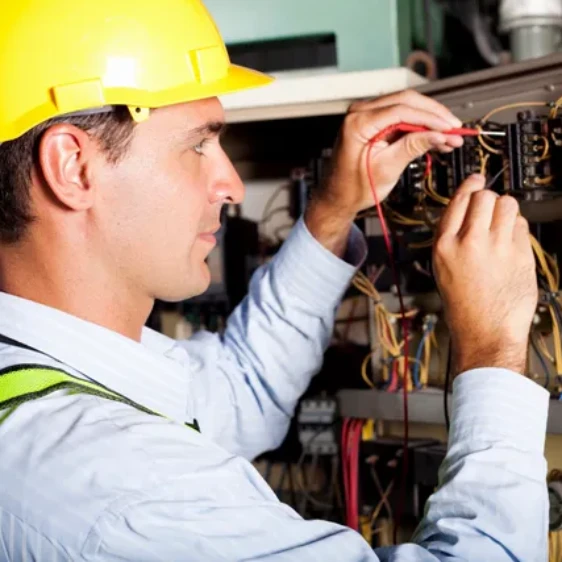 A man in yellow hard hat working on wires.